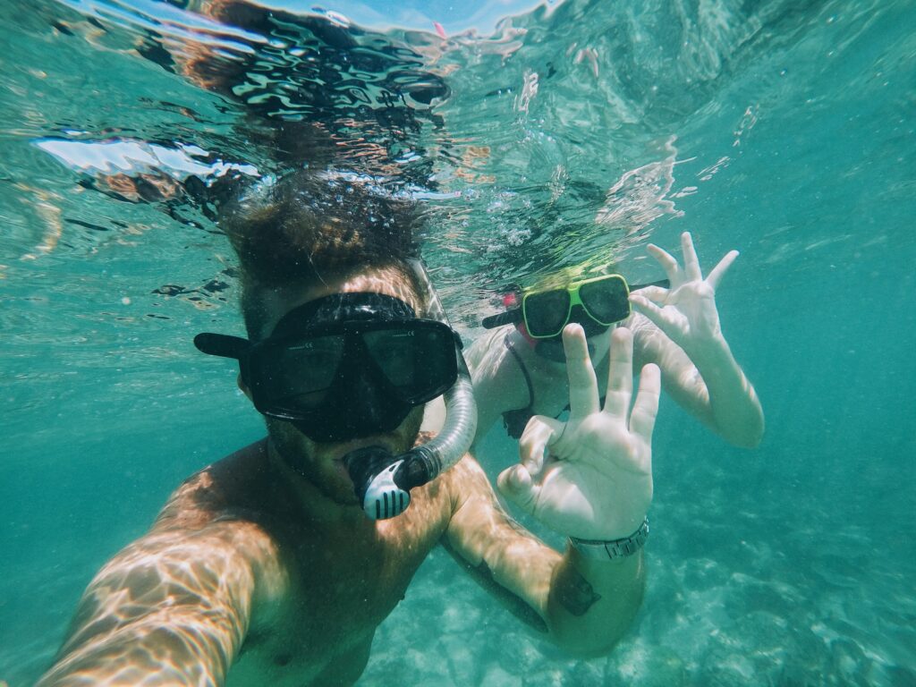 A man and a woman are underwater, both wearing scuba gear
